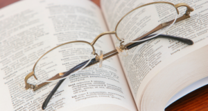 a photo of a pair of wire rimmed glasses resting on an open thesaurus
