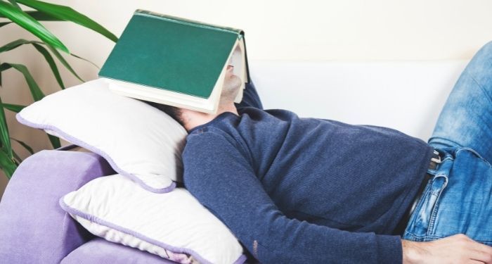 Image of a white person with a book covering their face