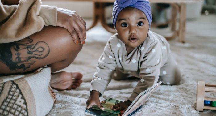 Image of a dark skin baby with a book