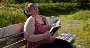 Image of a fat girl reading and laughing outside