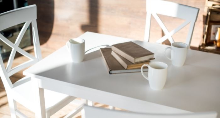 image of white chairs and table. books are in the center of the table.