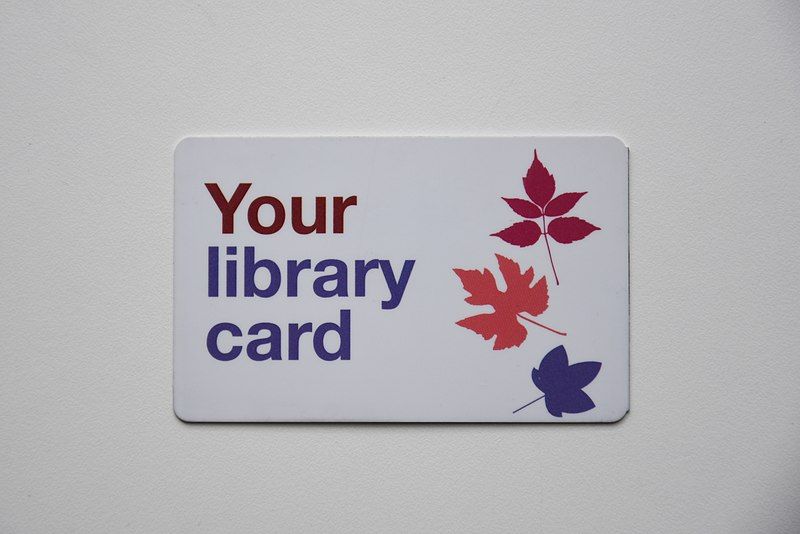 a white library card with three colorful leaves on the front