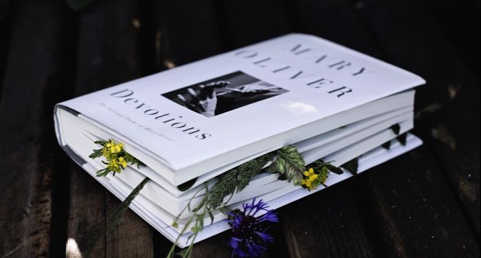 a hardcover copy of Devitions by Mary Oliver with flowers pressed between its pages