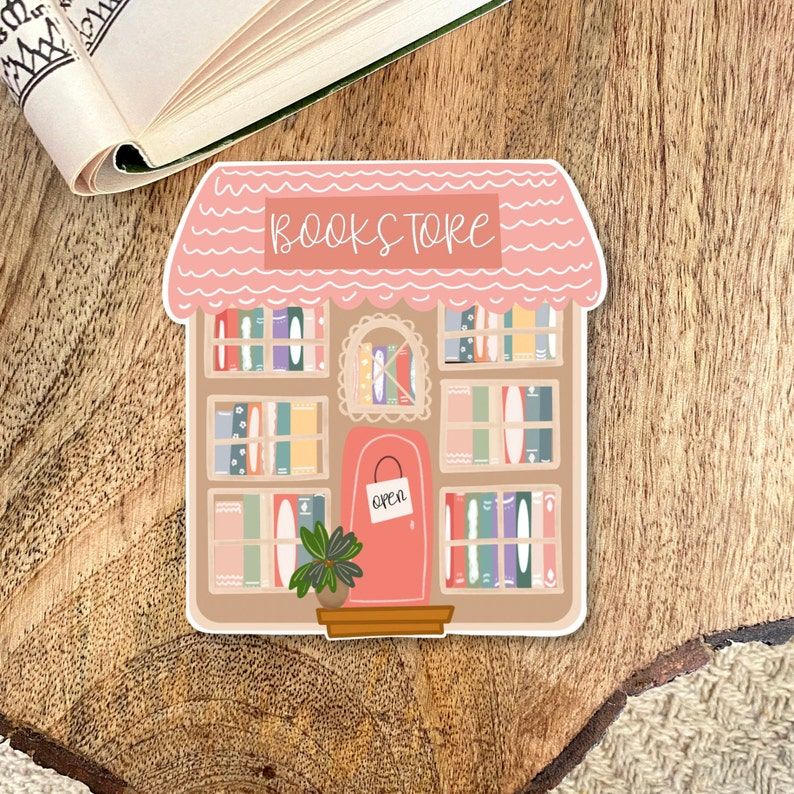Image of a bookstore sticker. It's a brown bookstore with pink roof and door. The windows are filled with book spines. 