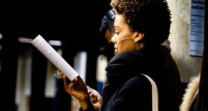 a photo of someone reading at a subway stop