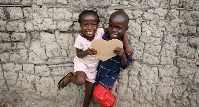 two smiling Black children holding a cardboard heart