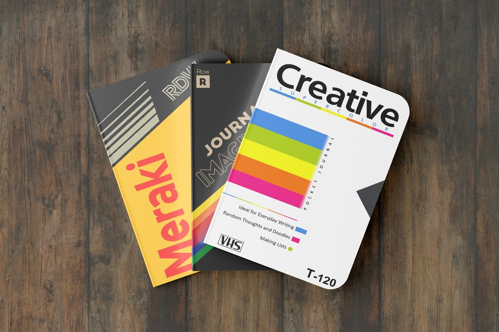 Image of three notebooks on a wooden background. The notebooks feature VHS tape covers. 
