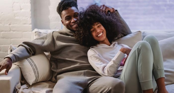 A black couple cuddling on a couch