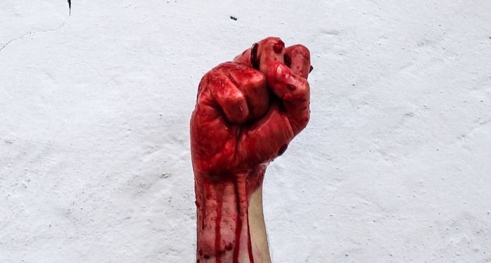 a bloody fist in front of a white hall