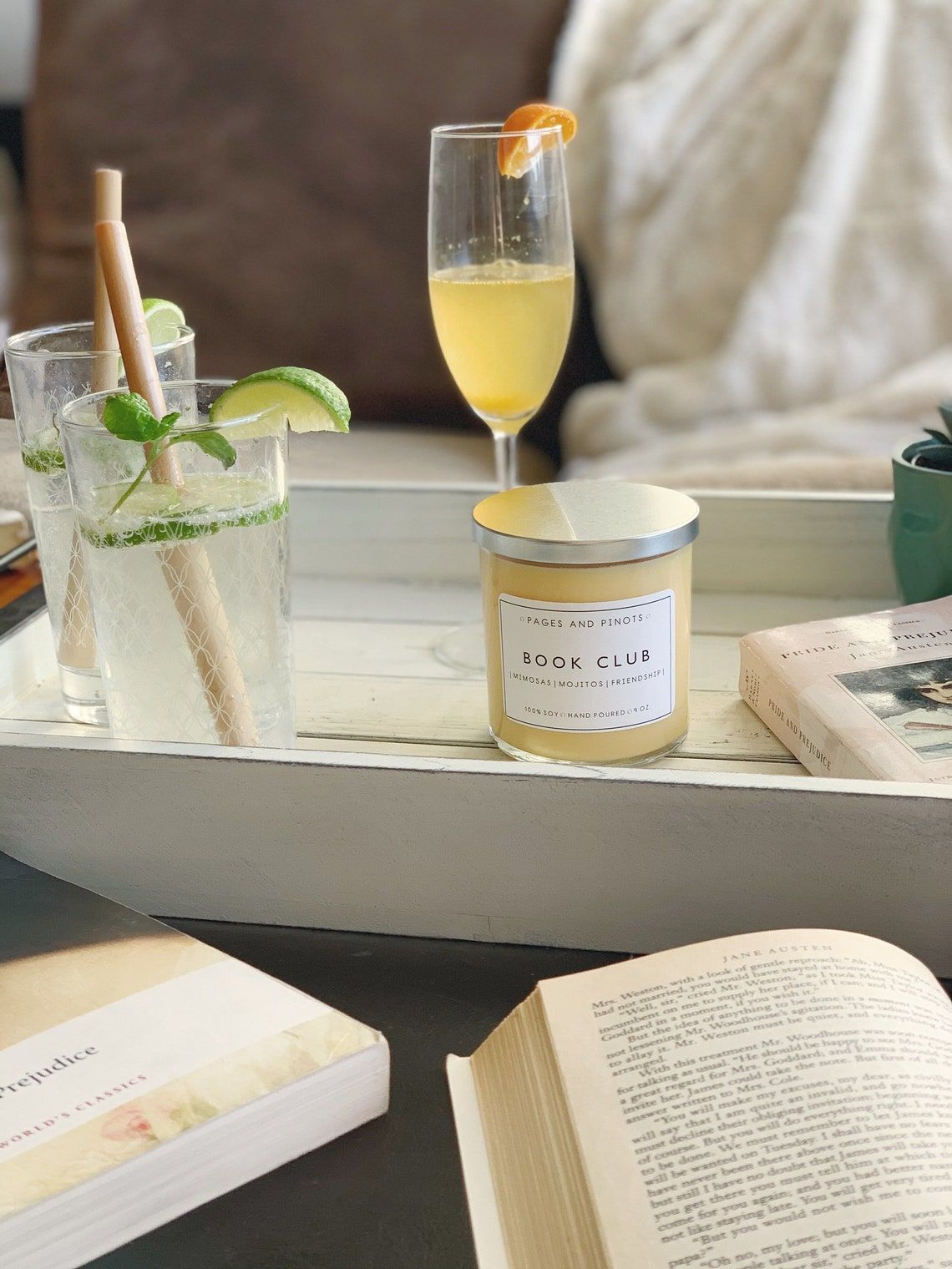 Image of a light yellow candle behind books and in front of a mimosa. 