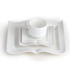A set of stacked white dinnerware (platter, dinner plate, dessert plate, sauce, and cup), all in the shape of an open book.