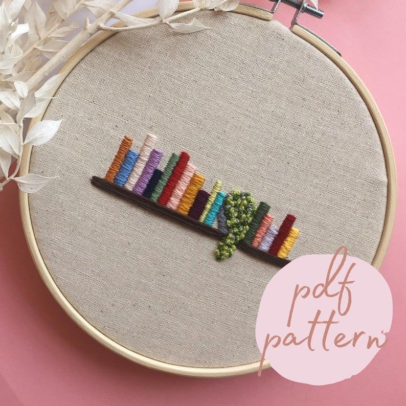 Image of an embroidery pattern featuring a shelf of colorful books. 