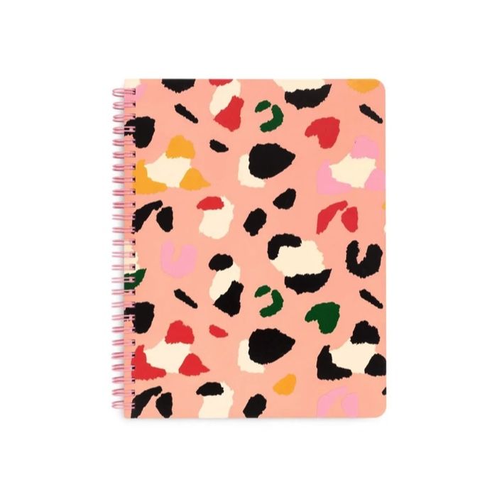 a salmon pink notebook with black, white, pink, green and yellow abstract shapes that look like cats