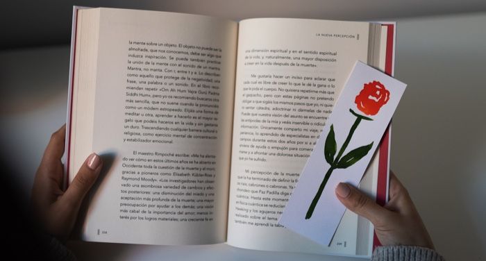 hands holding an open book with a paper bookmark in the right hand