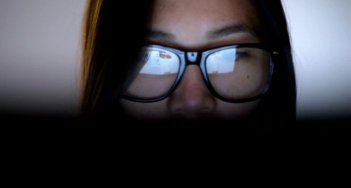 Image of a person wearing glasses, whose laptop screen is reflected in them.