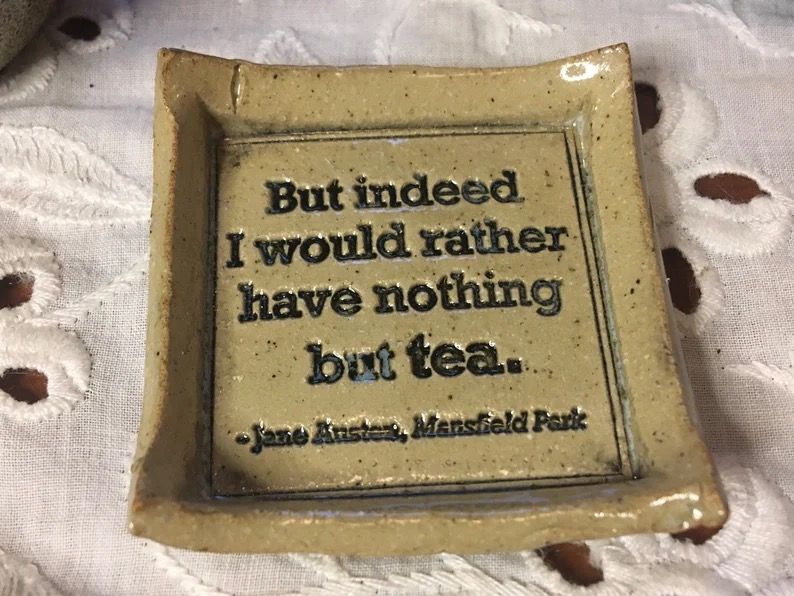 A small square ceramic tea bag holder with a Jane Austen quote.