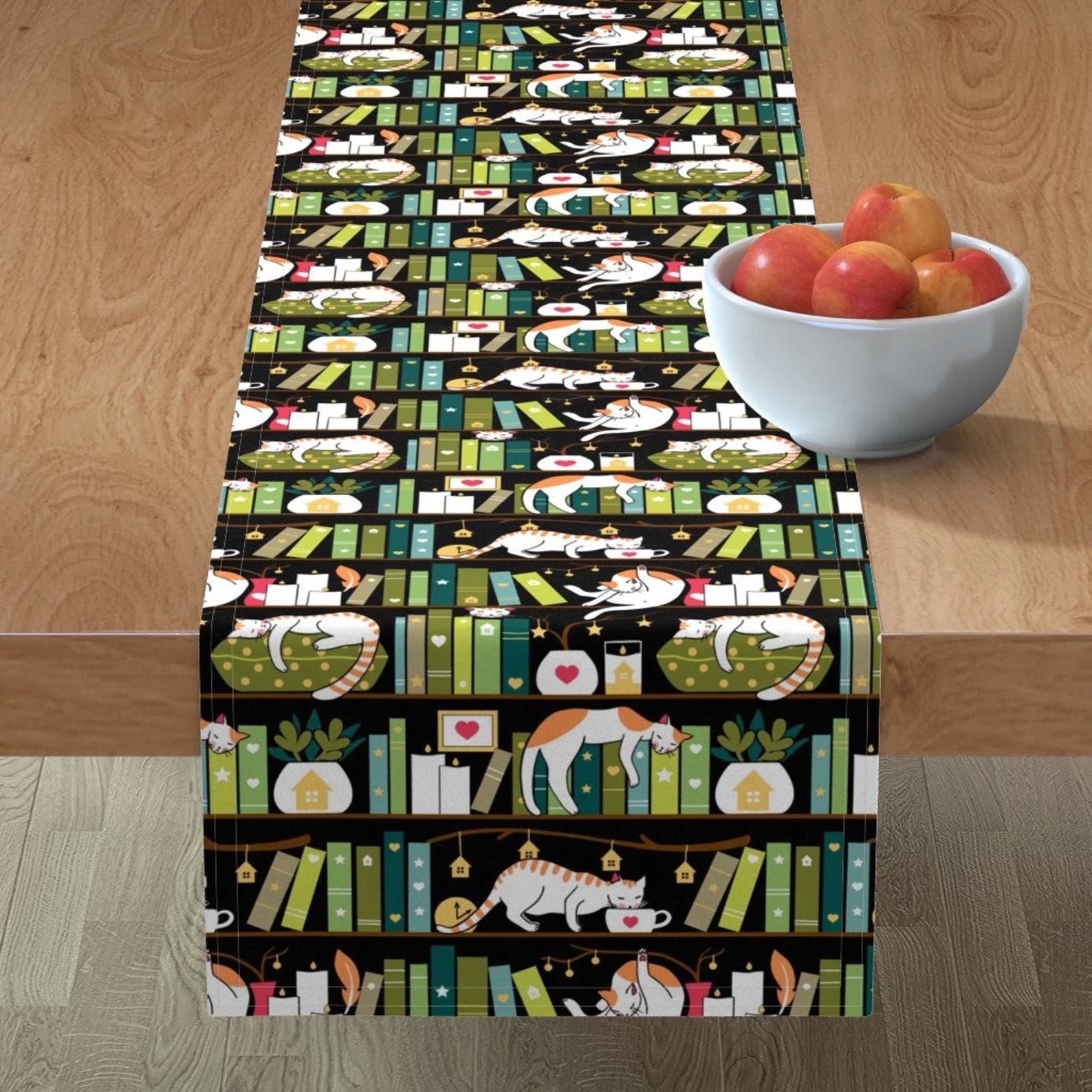 A cloth table runner with a pattern of books lounging among stacks of library books.