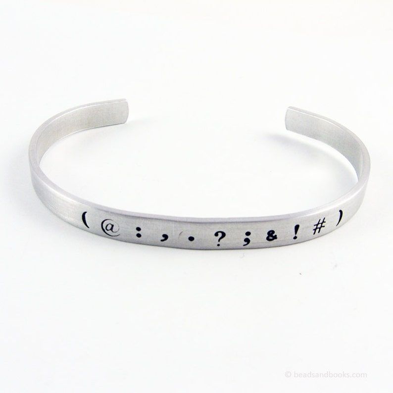 A silver cuff bracelet with punctuation marks