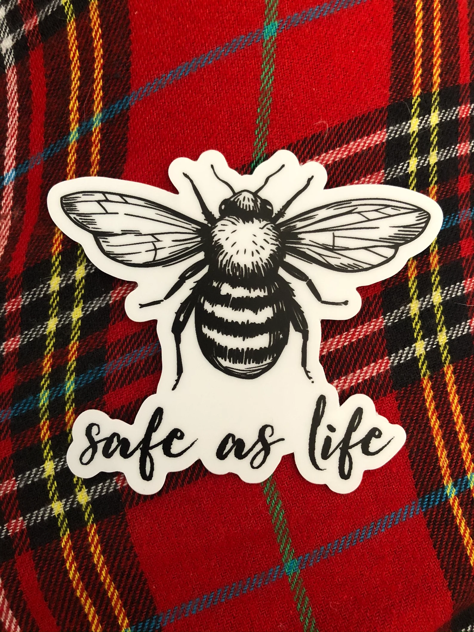A vinyl sticker depicting a bee and the words "Safe as Life"