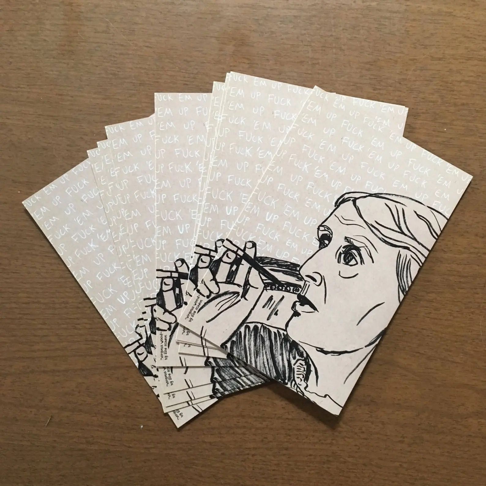 Postcard with a black and white drawing of Virginia Woolf tapping a pencil against her lips. The words "fuck 'em" appear over and over again in small white text in the background.