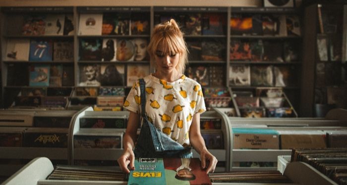 pale-skinned woman looking at a musical record in a record shop