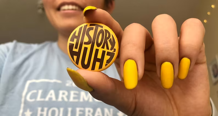 a photo of someone holding a yellow button reading History, Huh?