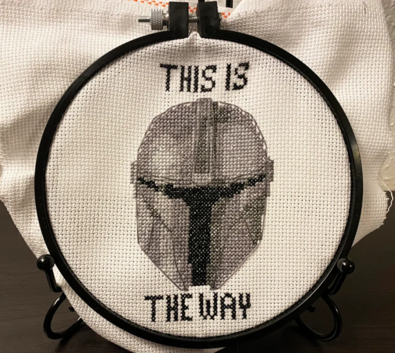 The Mandalorian helmet cross stitched on an embroidery hoop