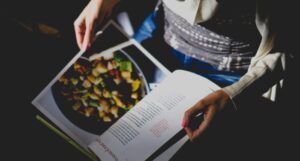 a person perusing a cookbook open to a roasted potatoes recipe