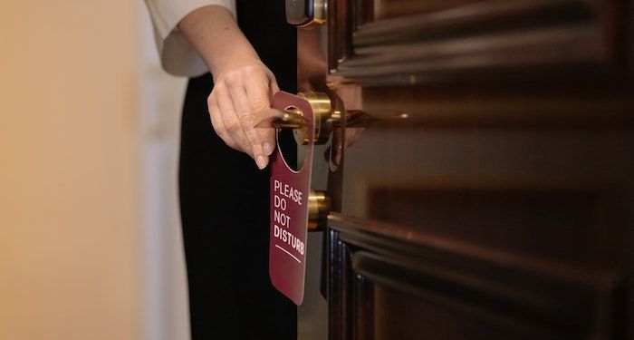 a photo of someone putting a Do Not Disturb sign on a hotel doorknob