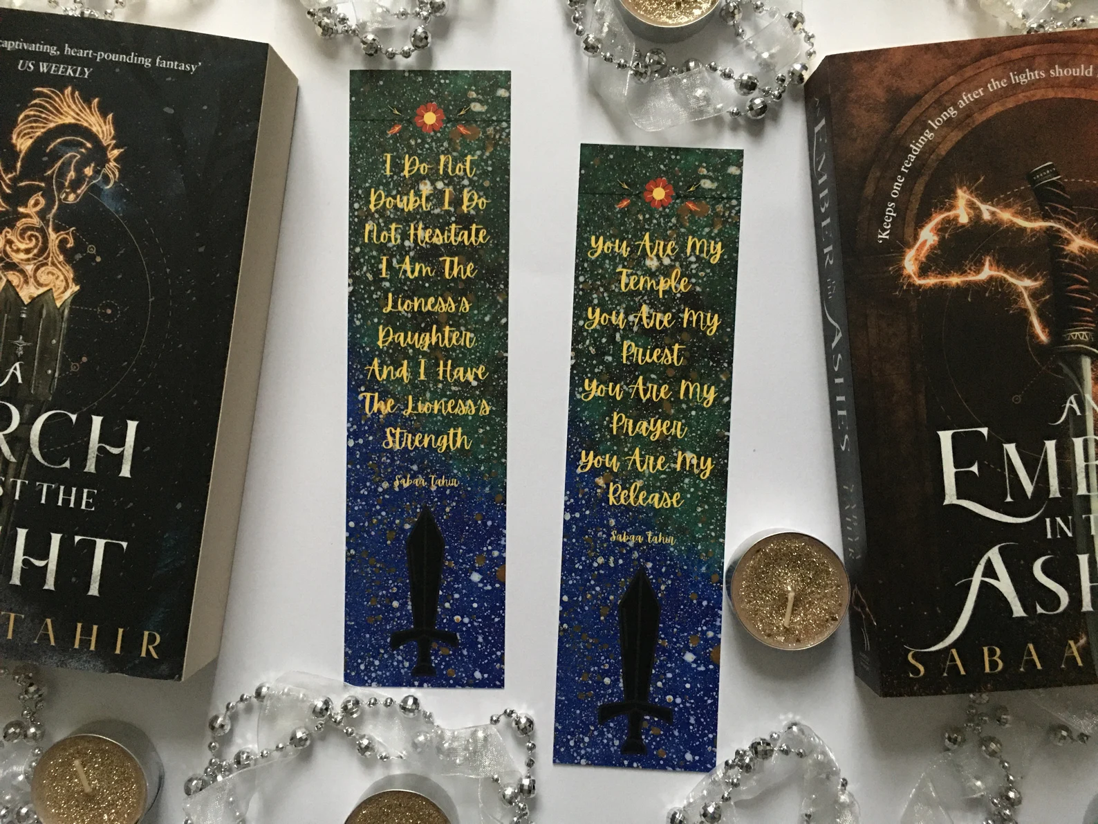 Two blue and green bookmarks with quotes from the books in gold text.