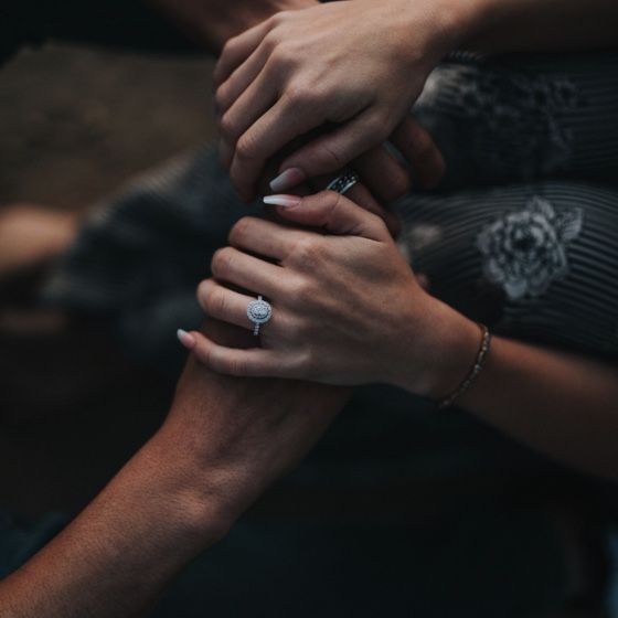 A couple holds hands with wedding rings on each partner's finger