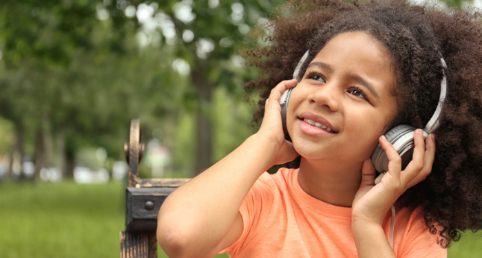 a photo of a kid listening to headphones in a park