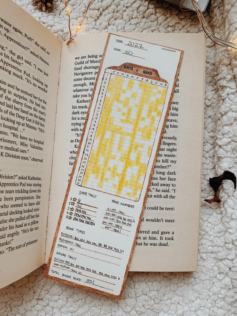Image of a cream bookmark inside an open book. The bookmark features check boxes for tracking reading habits. 