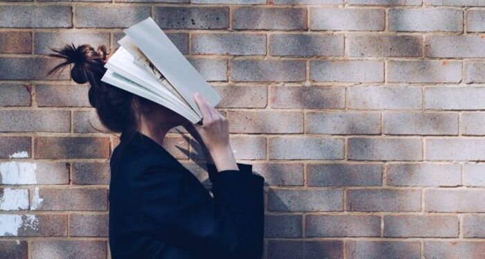 woman covering her face with white book