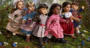 American girl dolls positioned standing next to each other on grass