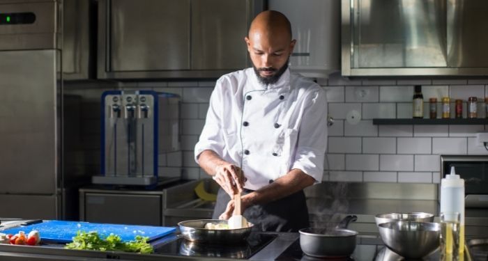 Black man in chef whites cooking in kitchen