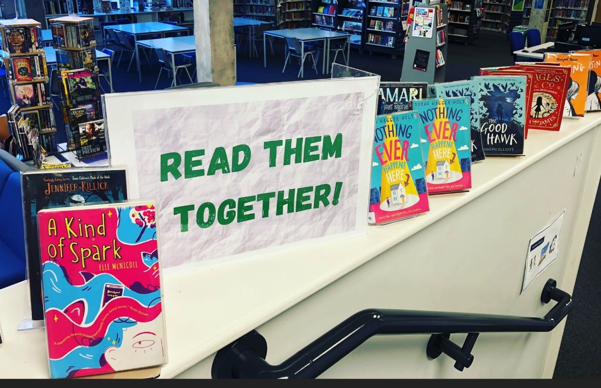 books on a shelf with a sign that says "read them together"