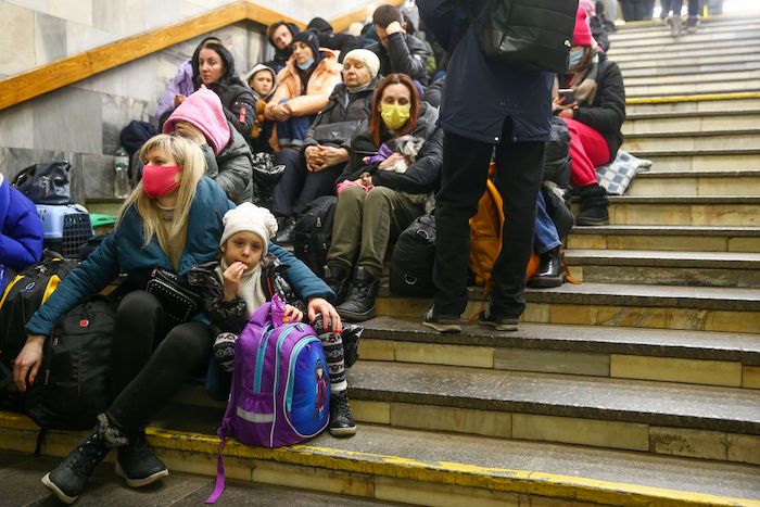 Ukrainian refugees, including adults and children, gathered on a flight of steps