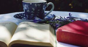tea cup in a saucer next to two books and a flower