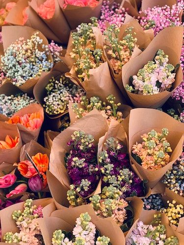 A selection of flowers in various colors wrapped in brown paper. (Source: Unsplash)