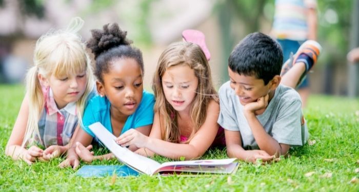 image of diverse children reading outside in the grass