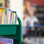 a green library cart full of childrens' books in public school library