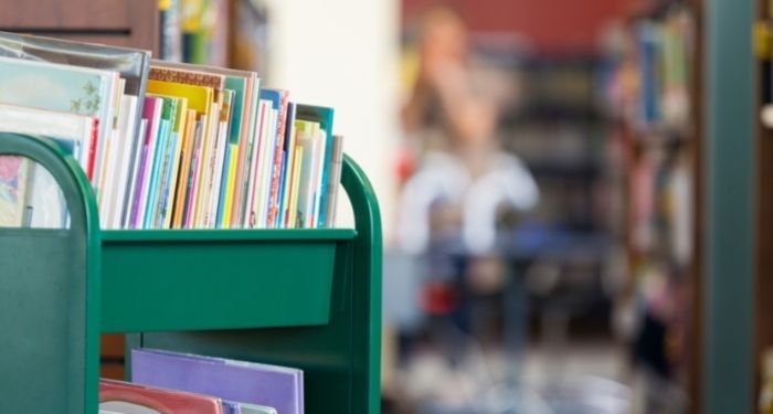 a green library cart full of childrens' books in public school library