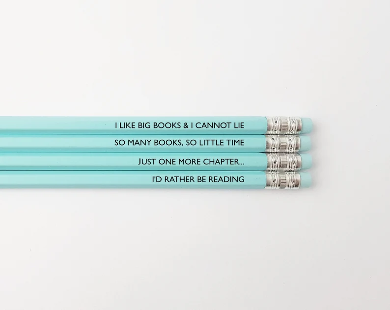 Set of four pastel blue pencils which all have black text. The text is a series of clever bookish sayings like "I'd rather be reading."