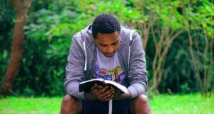 brown-skinned man reading on stone seating outside