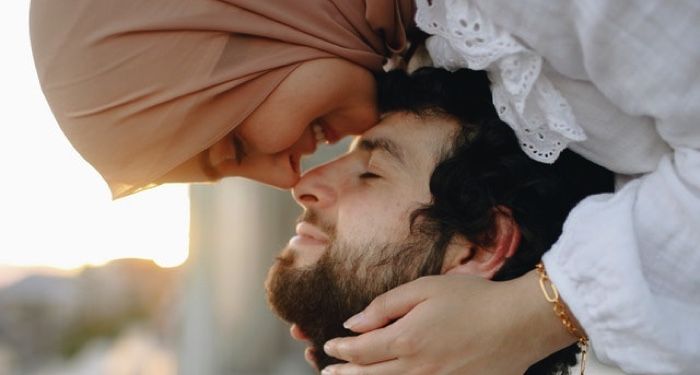 woman in hijab and man touching noses sweetly