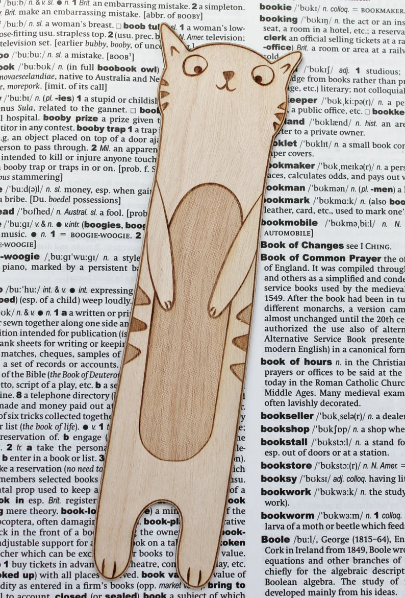 Image of a wooden cat bookmark on top of a dictionary page opened to the book-themed words. 