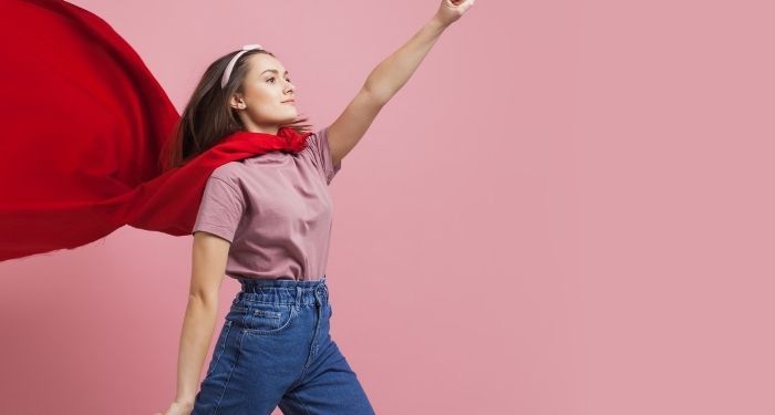 young, light-skinned woman in a red cape and jeans