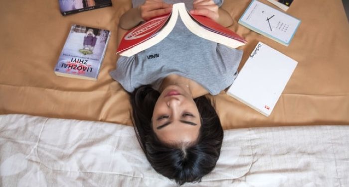 Asian lady lying down reading