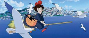 a still from Kiki's Delivery Service showing her on a broom with a cat smiling at seagulls flying by over the water